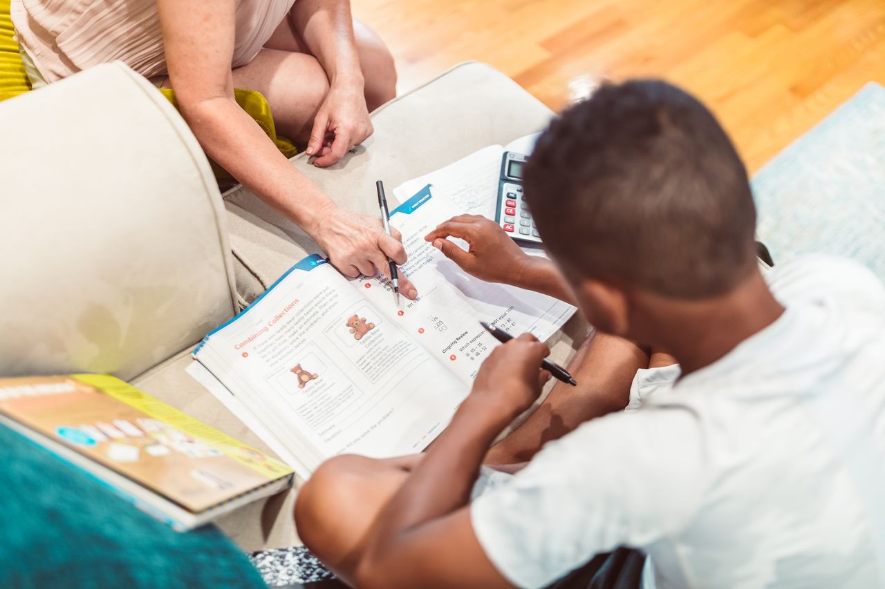 A child receives tutoring assistance with homework, highlighting education and learning.
